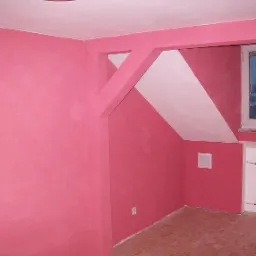 Pokój po malowaniu na różowo z białym akcentem w rogu, widoczny grzejnik i okno z widokiem na zewnątrz.